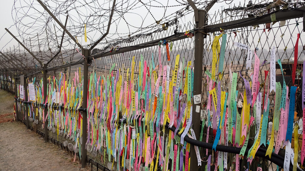 The fence is strewn in ribbons praying for unification.